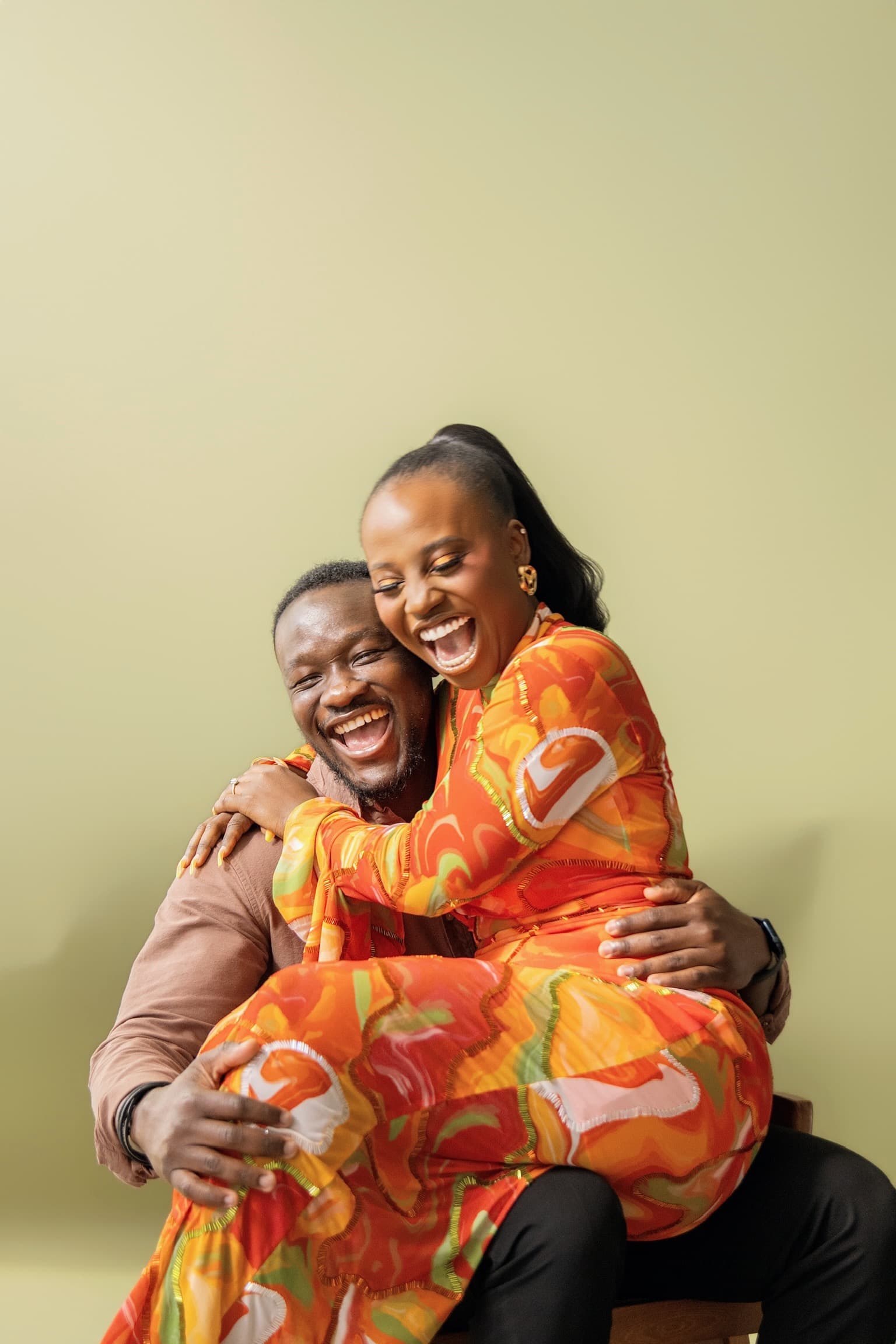 Juwon and Femi laughing together in a warm embrace